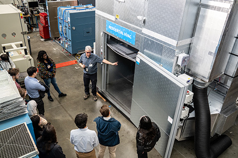 Scientists show a group of students inside an HVAC testing chamber.
