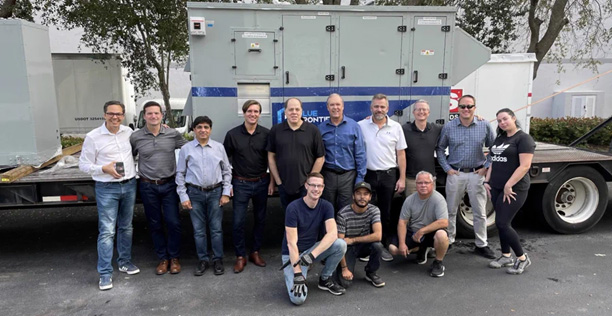 A group of employees stand in front of an HVAC system.