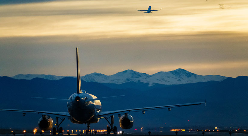 Airplanes take off in front of mountains.
