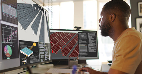 A man sits in front of dual computer monitors.