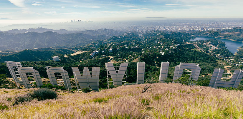 The back of the Hollywood sign with a mountainous city in the background.