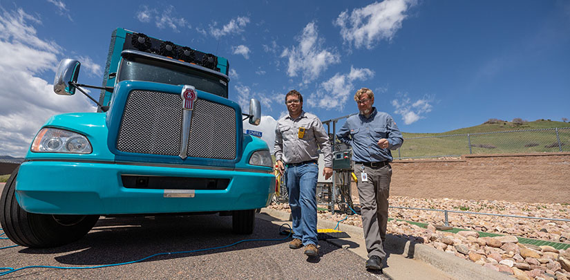 NREL researchers Matthew Post and Owen Smith walk alongside each other while the H2Rescue vehicle is refueling.