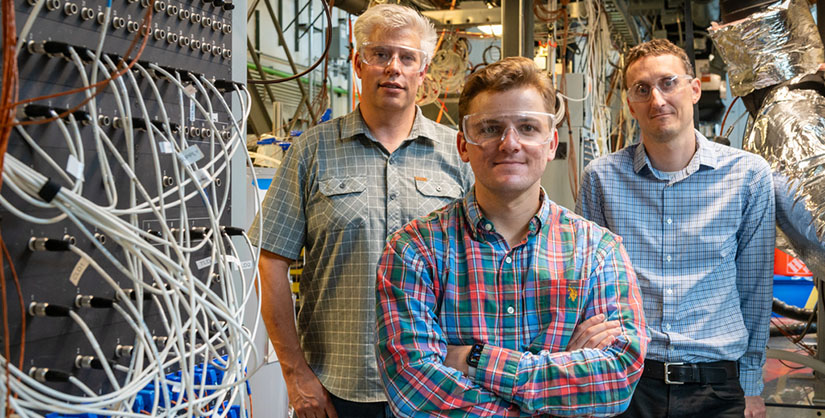 Three men standing next to wires.