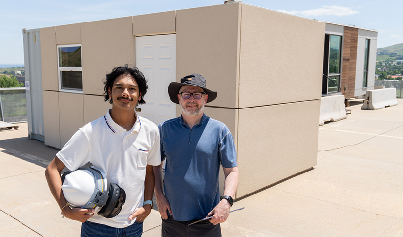 Two men standing outside smiling.