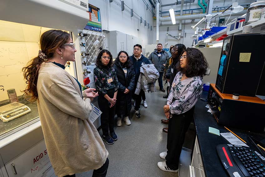 Researcher speaking with students in a lab.