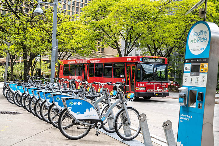 Bicycles parked on the sidewalk with a bus in the background.