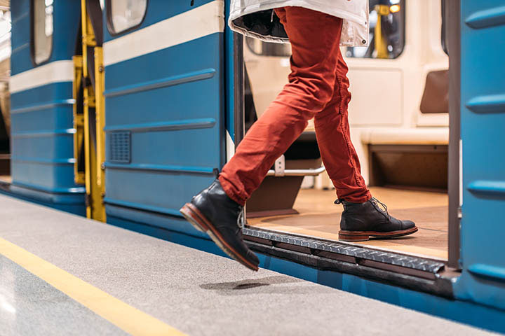 A person wearing red pants walking onto a public train.