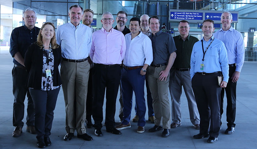 A line of researchers and industry leaders pose with Phoenix Sky Harbor International Airport employees.