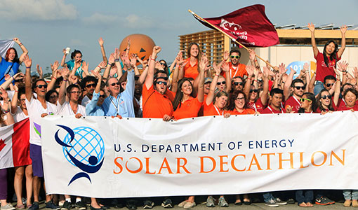 Dozens of competitors hold a Solar Decathlon banner and smile.