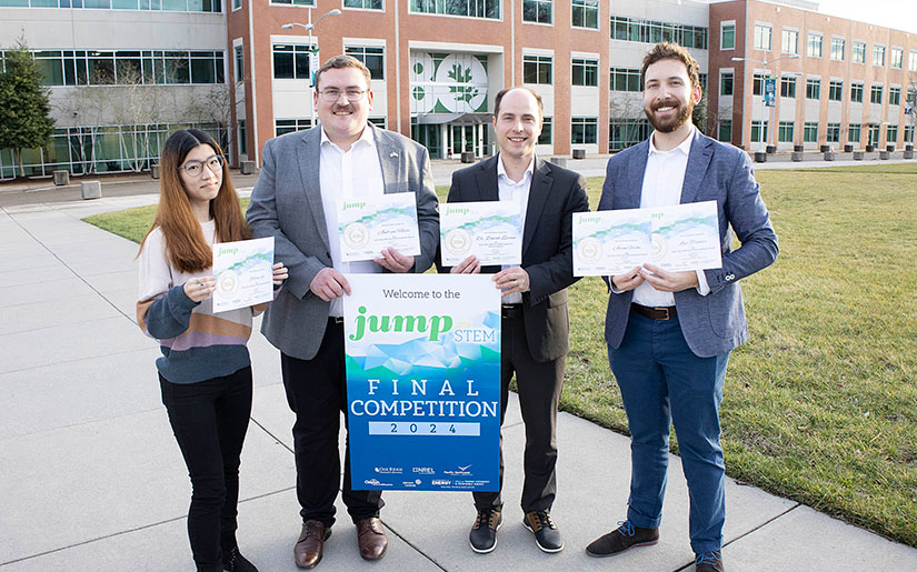 Four people holding certificates and standing outside.