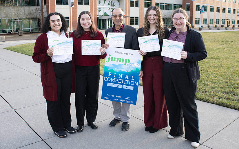 Five people holding certificates while standing outside.