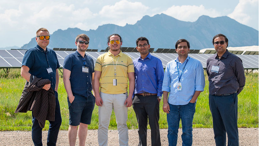 Six people posing in front of solar panels.