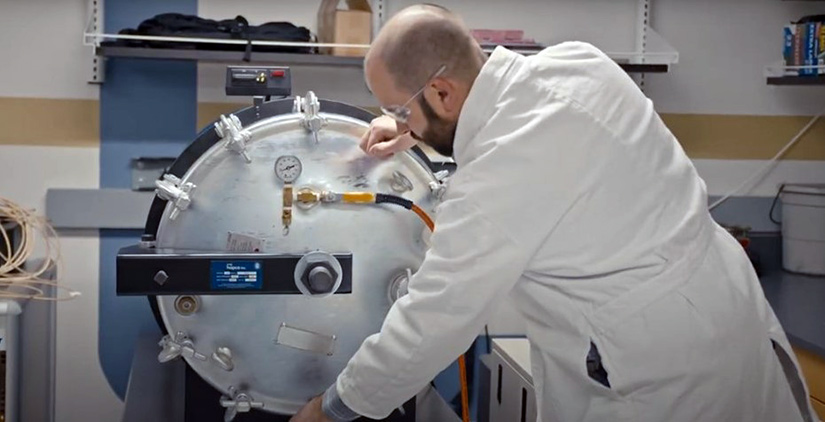 A man in a lab coat works on research equipment