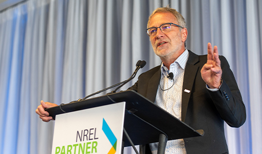 A person speaking at a podium with a sign that reads NREL Partner Forum.