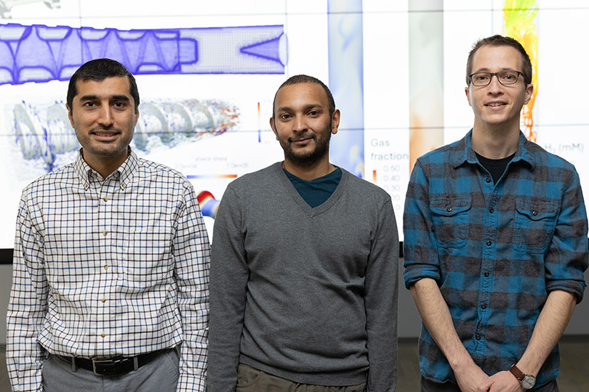 Three people standing in front of a data visualization