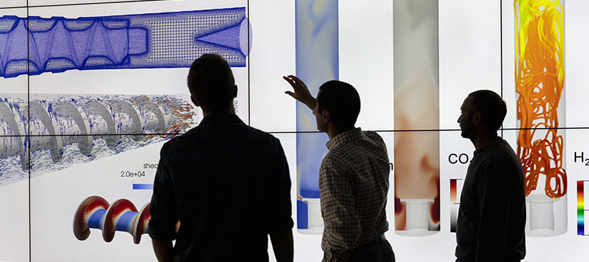 A group of silhouetted people looking at a screen