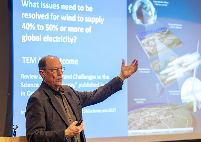 Paul Veers presents in front of a projector screen that says, “What issues need to be resolved for wind to supply 40% to 50% or more of global electricity?”