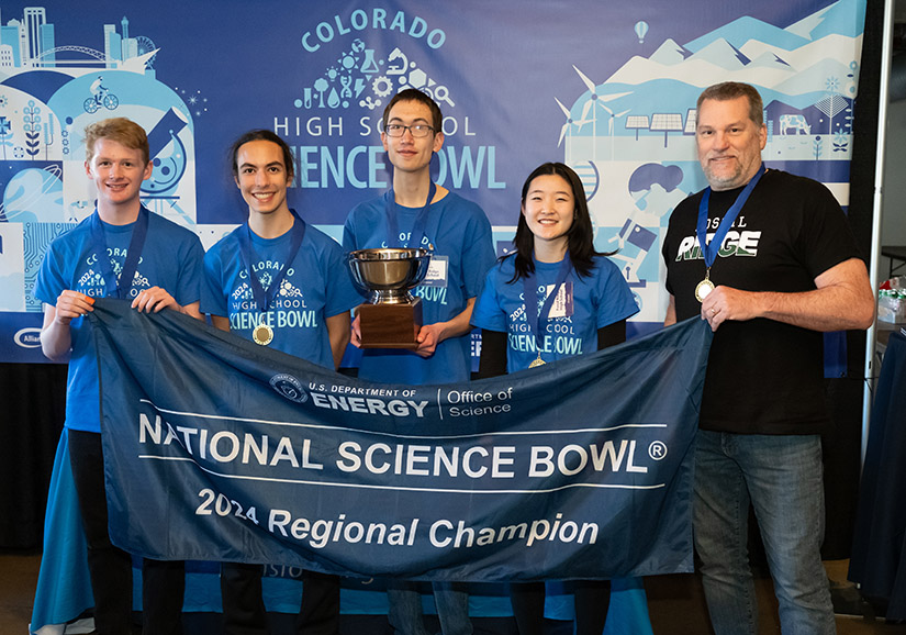 Four students and a teacher hold up a banner that reads National Science Bowl 2024 Regional Champion.