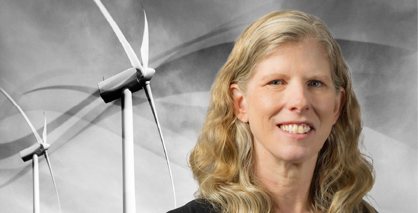A headshot of Amy Robertson in front of two wind turbines.