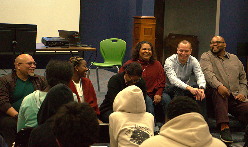 Six people sit facing students smiling and laughing. 