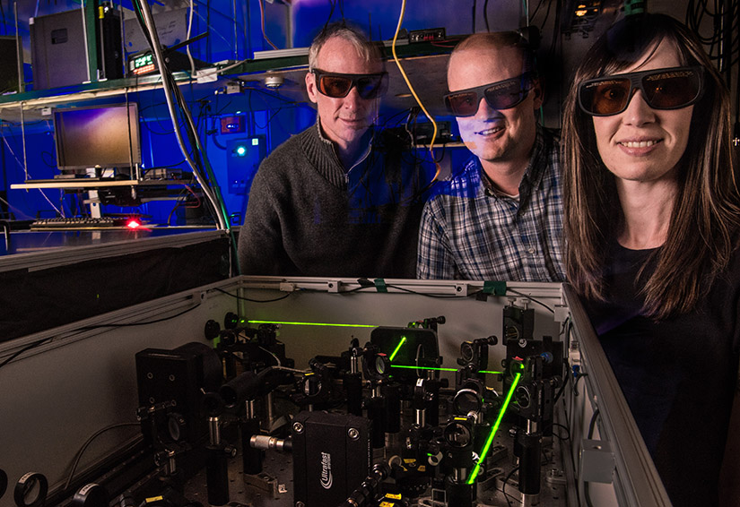 Three people wearing protective tinted glasses in a lab.