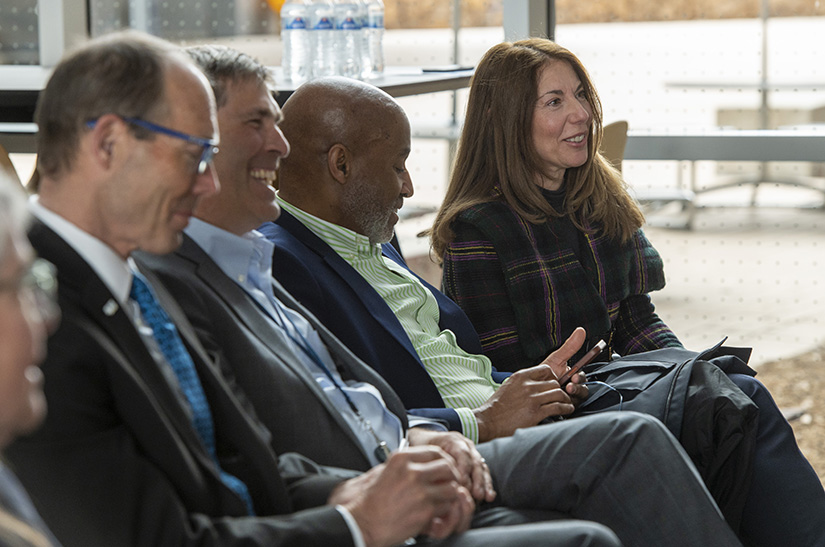Four people sitting in a row, smiling.