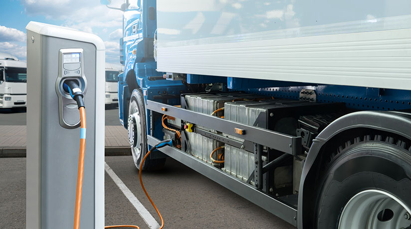 An electric commercial vehicle charging at a charging station.