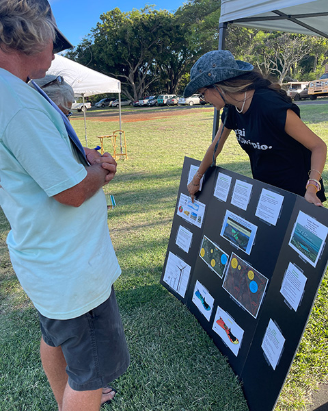 Two people outside looking at a decorated poster board. 