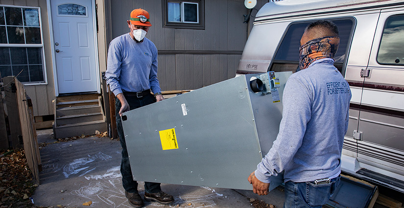Two men carrying a furnace into a home.