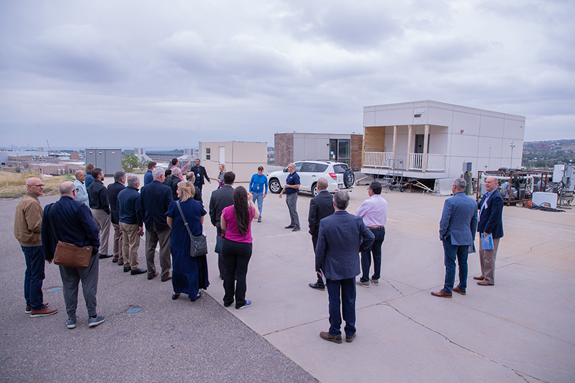Shanti Pless speaks to a group of people in front of a modular apartment prototype.