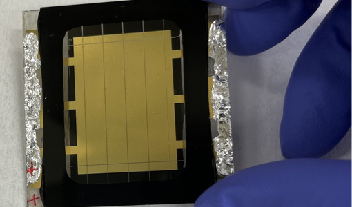 A gloved hand holds a perovskite solar cell.