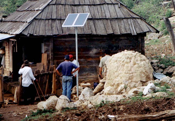 A small ground-mounted PV panel outside a small hut.