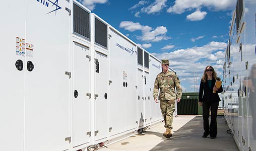 A man and woman walk next to Fort Carson's utility scale lithium ion Battery Energy Storage System (BESS) installation.
