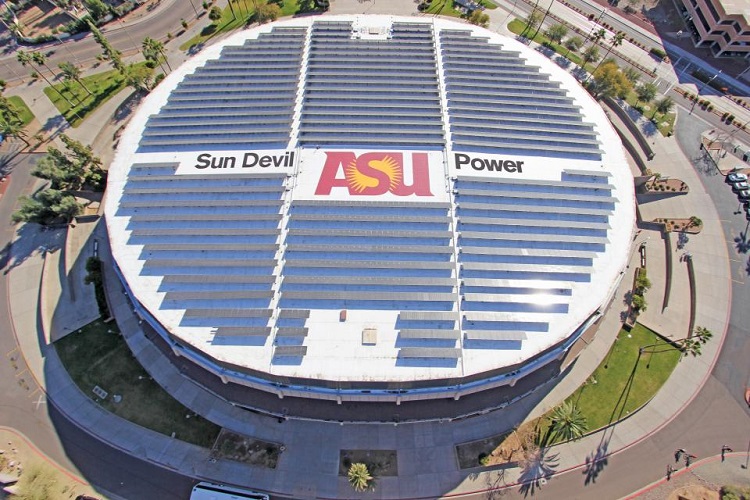 An aerial view of a sports arena with a large solar array on the roof.