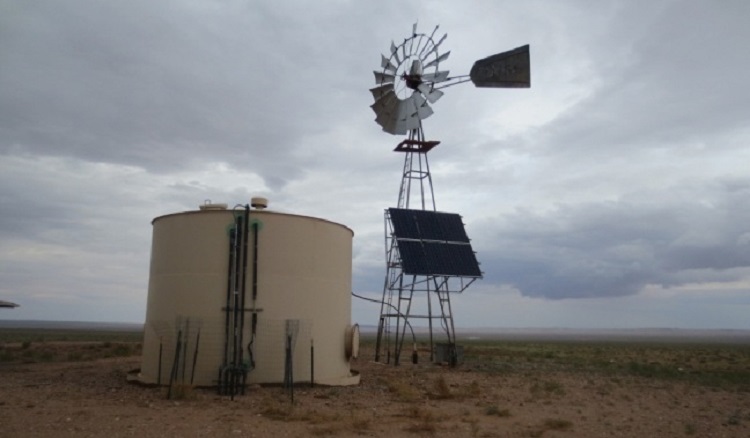 A water system holding tank and windmill with solar panels.