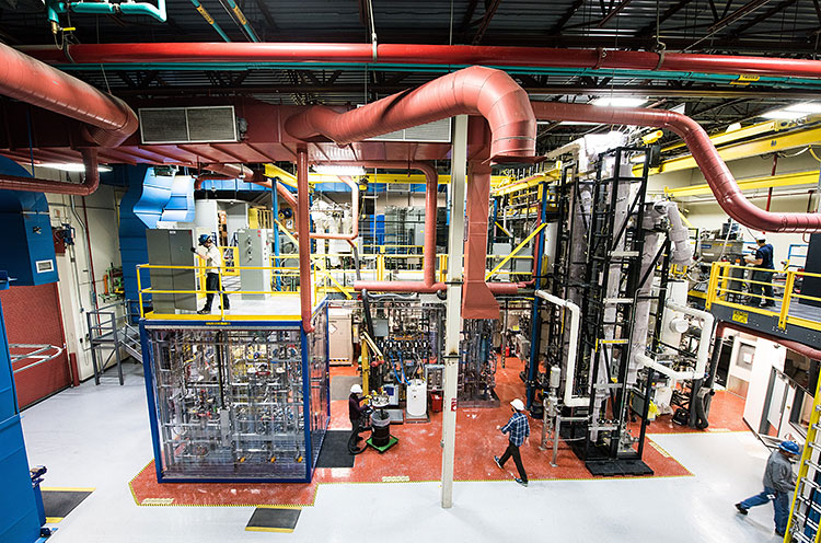 Engineers walk and work among the pipes and tubes of NREL’s Thermal and Catalytic Process Development Unit.