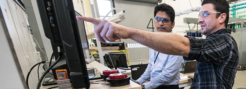 Two NREL researchers perform cyber security testing in a laboratory.
