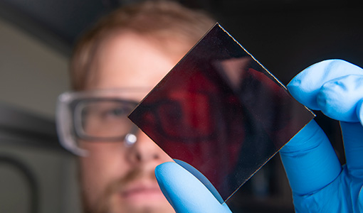 A researcher holding a solar thin-film square.