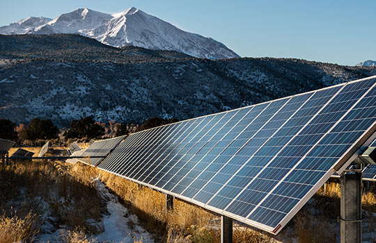 Solar panels with mountains in the background.
