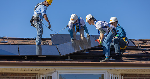 People installing rooftop solar panels on a house