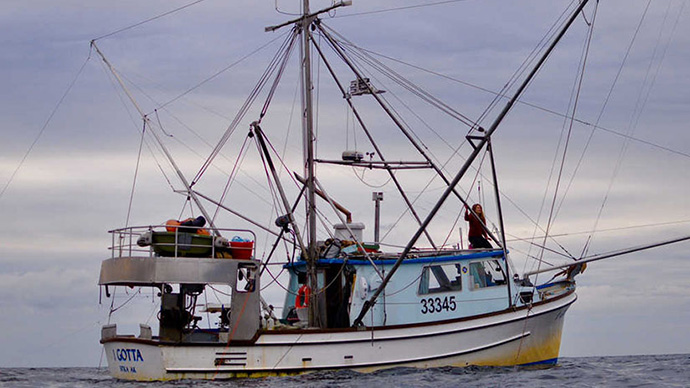 An image of a fishing vessel on the sea under cloudy skies.