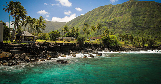 Molokai island shoreline with buildings and mountain in background