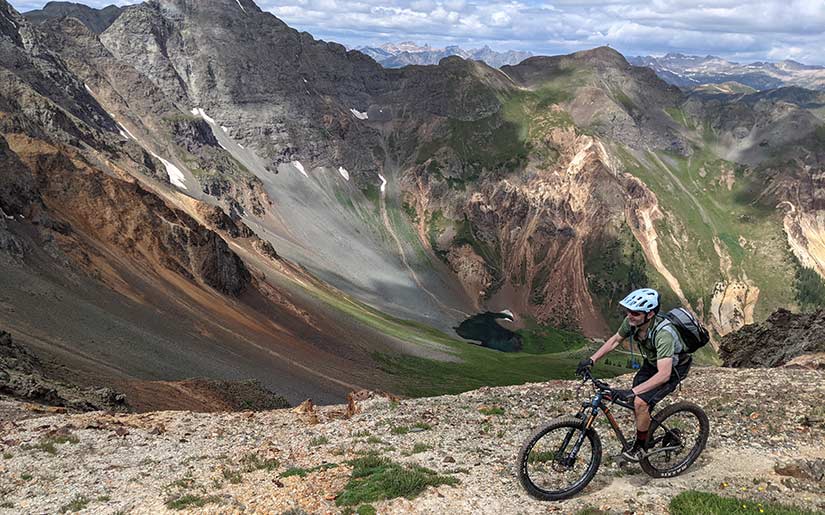 A photo of a person on a bicycle in front of mountains.