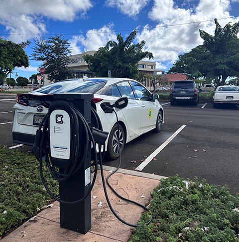A white electric car plugged into a charger.