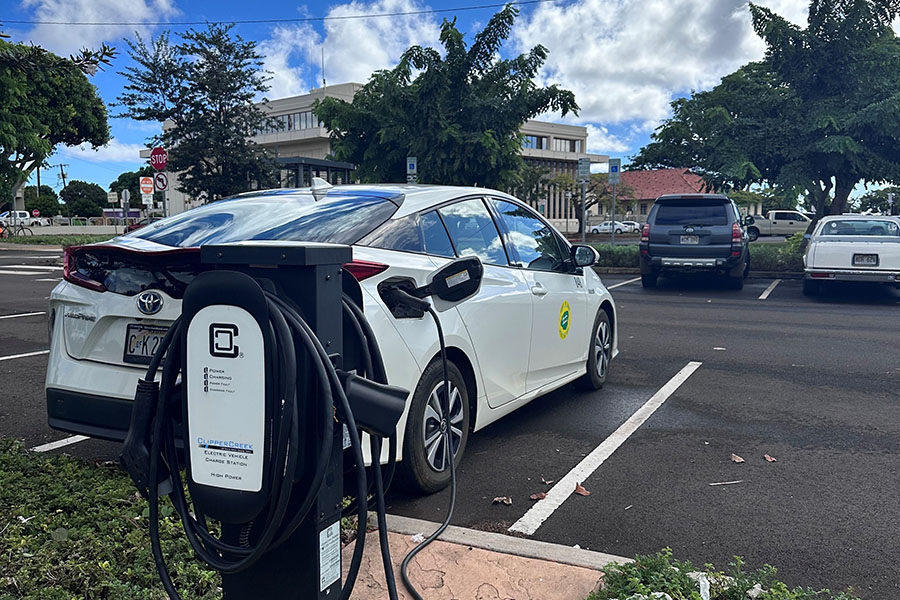 Electric vehicle plugged into a charging station at a parking lot.