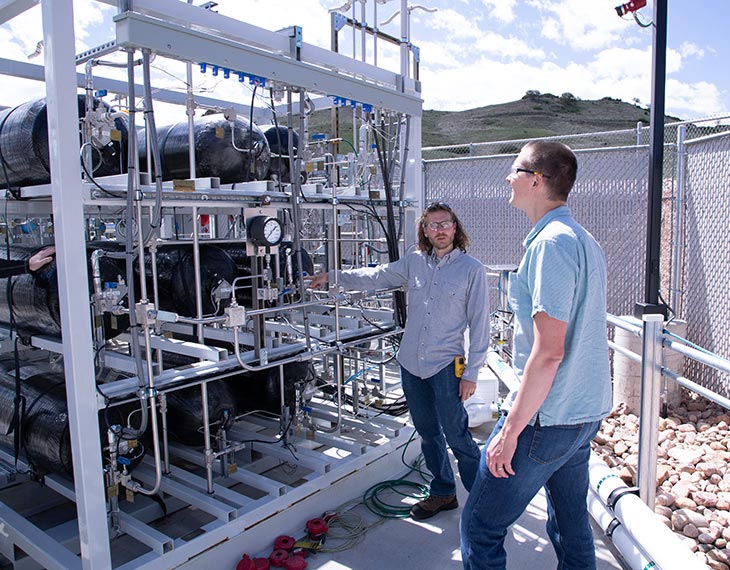 Two researchers stand in front of NREL's heavy-duty hydrogen fueling station.