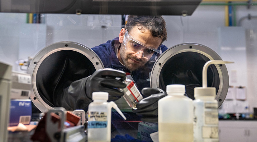 A researcher uses a laboratory glove box to examine battery materials.