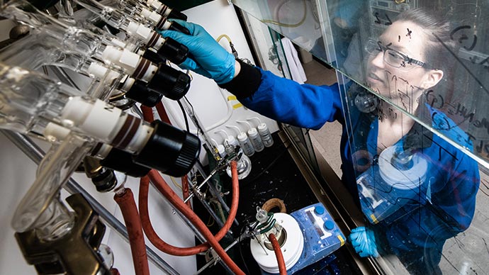 Researcher adjusting lab equipment to combine materials with silicon nanoparticles.