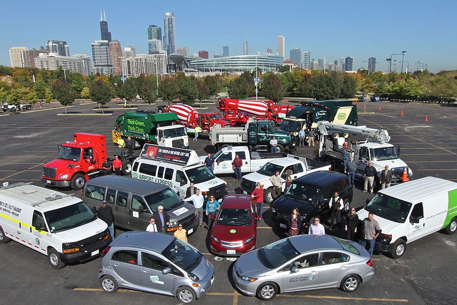 A cluster of vehicles with a group of people interspersed between them.