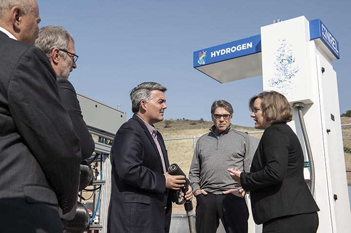 Four men and one woman talk in front of a hydrogen fueling station at the National Renewable Energy Laboratory.